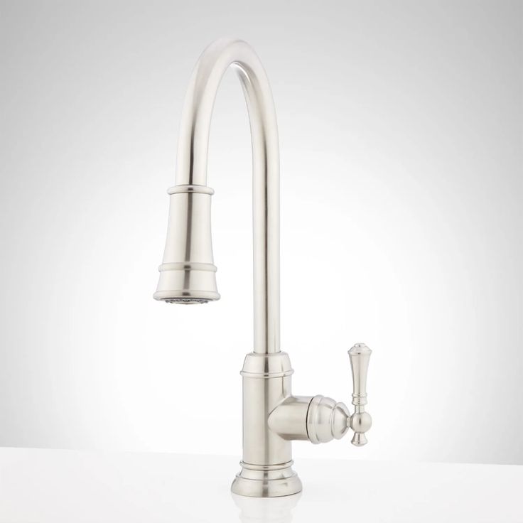 a kitchen faucet that is on top of a white countertop and has an open spout