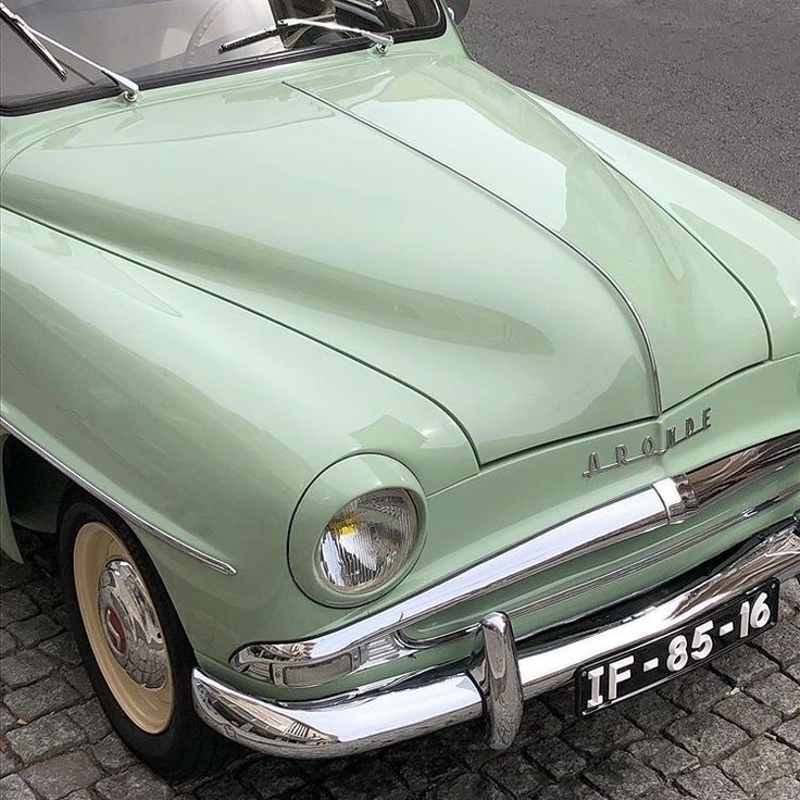 an old green car is parked on the street