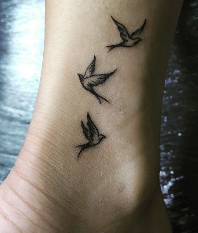 a small tattoo on the foot of a woman with three birds flying above her feet