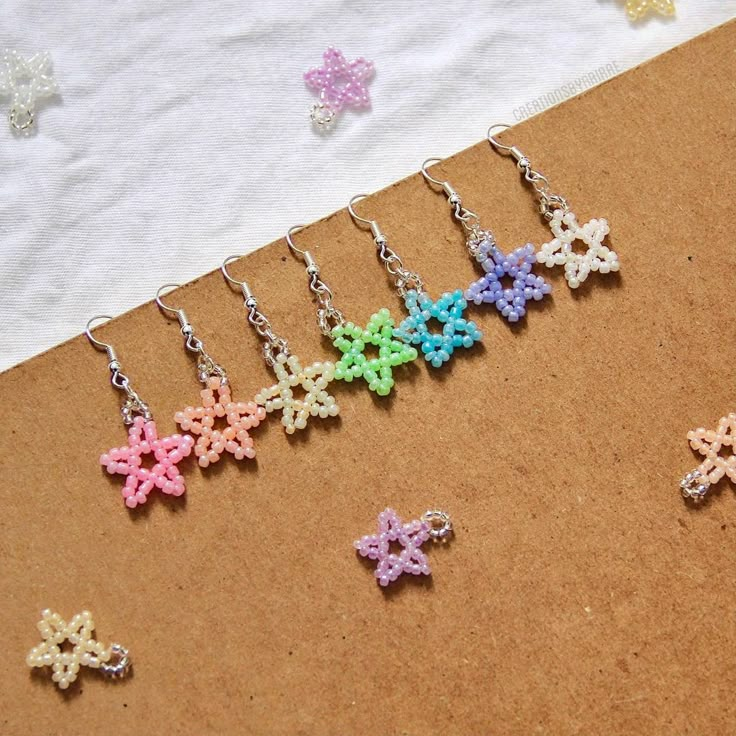 six small crocheted flowers are hanging from hooks on a piece of paper next to a pair of scissors