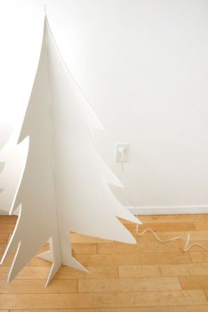 a white christmas tree sitting on top of a hard wood floor next to a wall