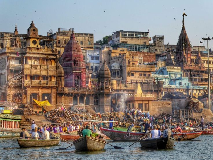 several boats floating on top of a body of water near buildings with spires in the background