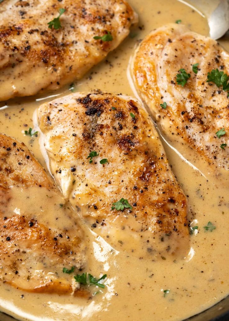 three pieces of chicken covered in gravy and garnished with parsley