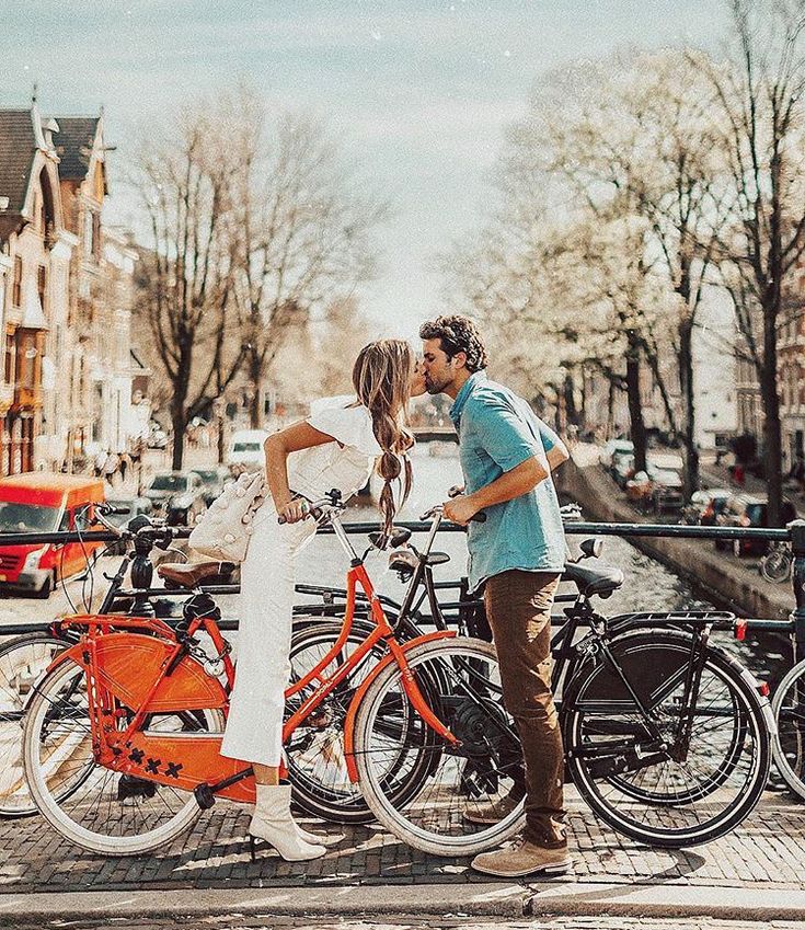 a man kissing a woman on the cheek while standing next to two bikes in front of them