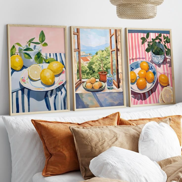 three paintings are hanging on the wall above a bed with pillows and throw pillows in front of them