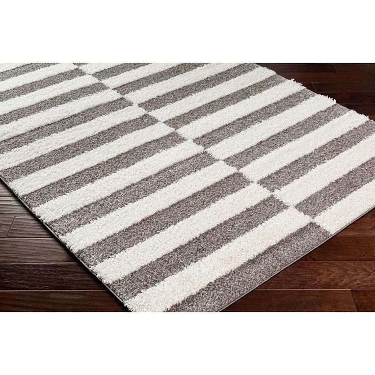 a gray and white rug on top of a wooden floor