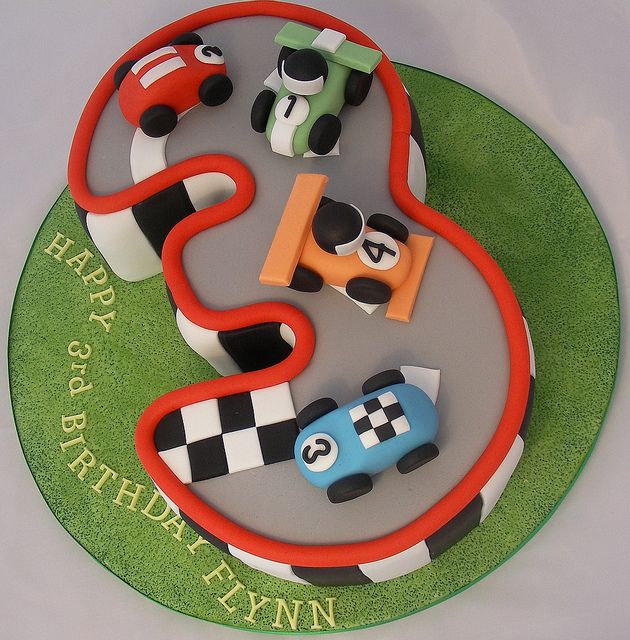 a birthday cake with cars and trucks on the top is made to look like a race track