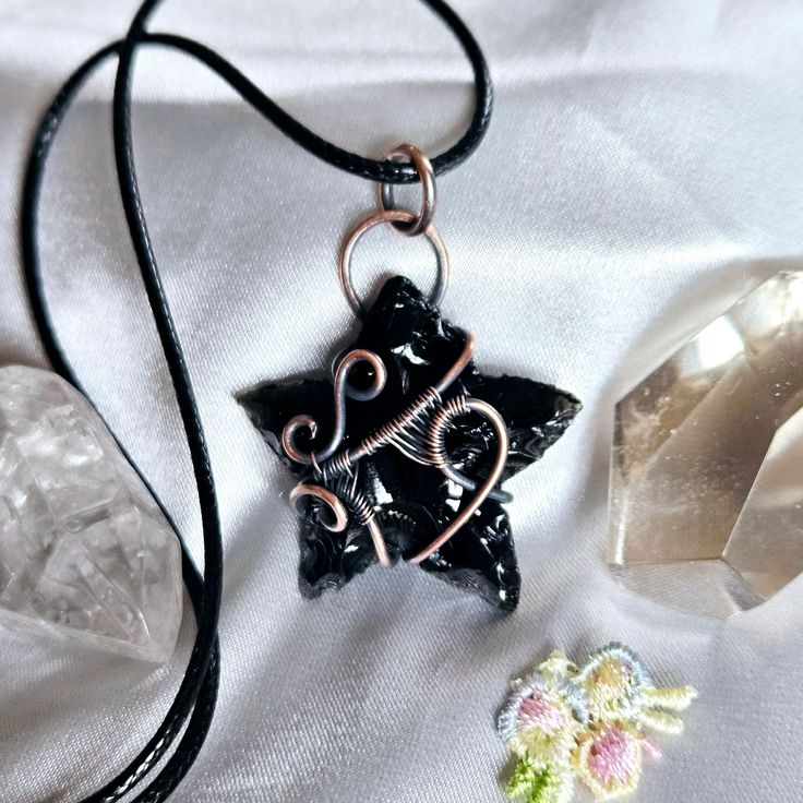 Introducing the ultimate statement piece, the Wire-Wrapped Black Obsidian Star Necklace. This piece is a true work of art, handcrafted with love and attention to detail.  The star of this necklace is a stunning black obsidian carving, carefully chosen for its unique chiseled texture that creates mesmerizing crevices and enhances the shine of the stone. It's like holding a piece of the night sky in your hands.  To make this necklace truly one-of-a-kind, I wire-wrapped the obsidian in pure copper, Cosmic Aesthetic, Aesthetic Pendant, Witchy Dress, Edgy Necklace, Obsidian Jewelry, Witchy Gifts, Visual Aesthetics, Wire Wrapping Crystals, Handmade Beauty Products