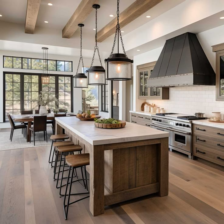 a large kitchen with an island, stove and dining table in the center is surrounded by wood flooring