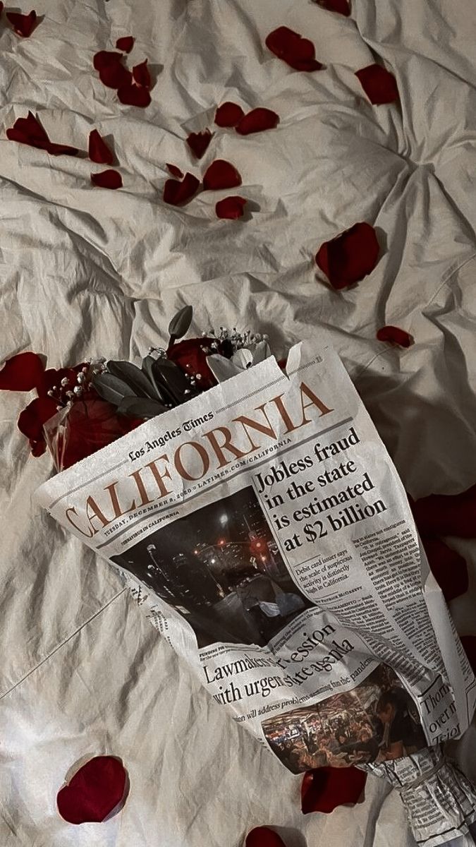 a newspaper laying on top of a bed covered in rose petals and petals scattered around it