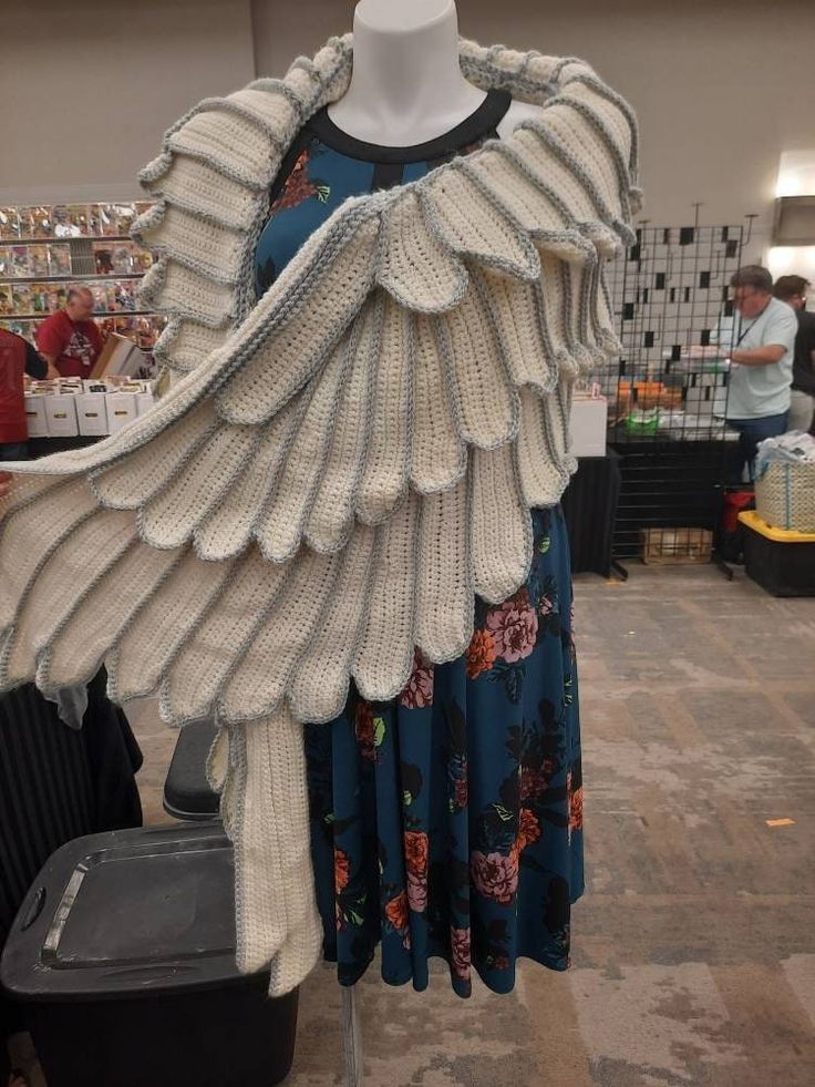 a mannequin dressed in white and black clothing with feathers on it's back