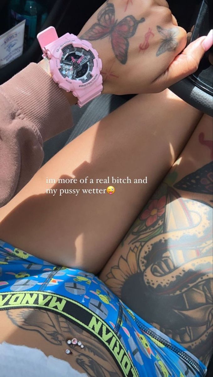 a woman with tattoos on her arm sitting in a car