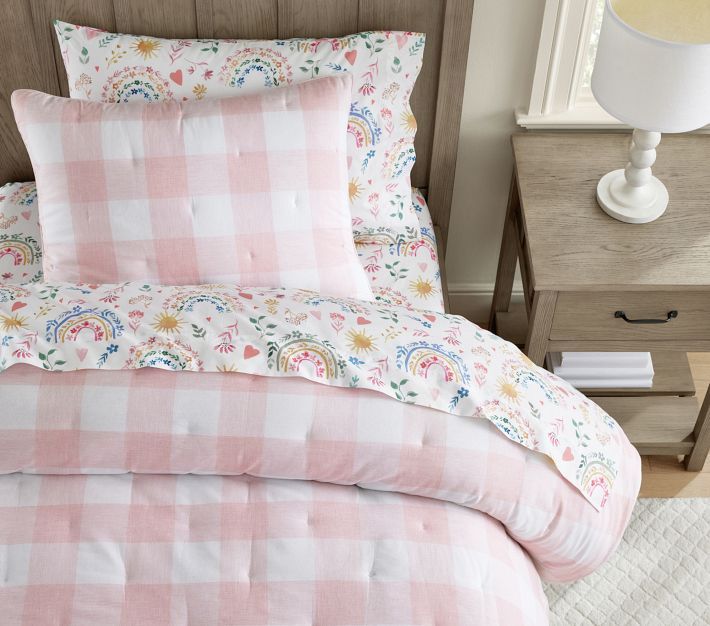 a pink and white checkered comforter set on a bed with two nightstands