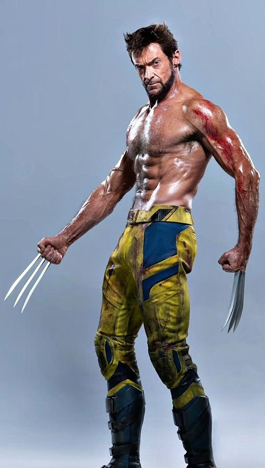 a man in yellow and blue wolverine costume with his hands on his hips, holding two claws