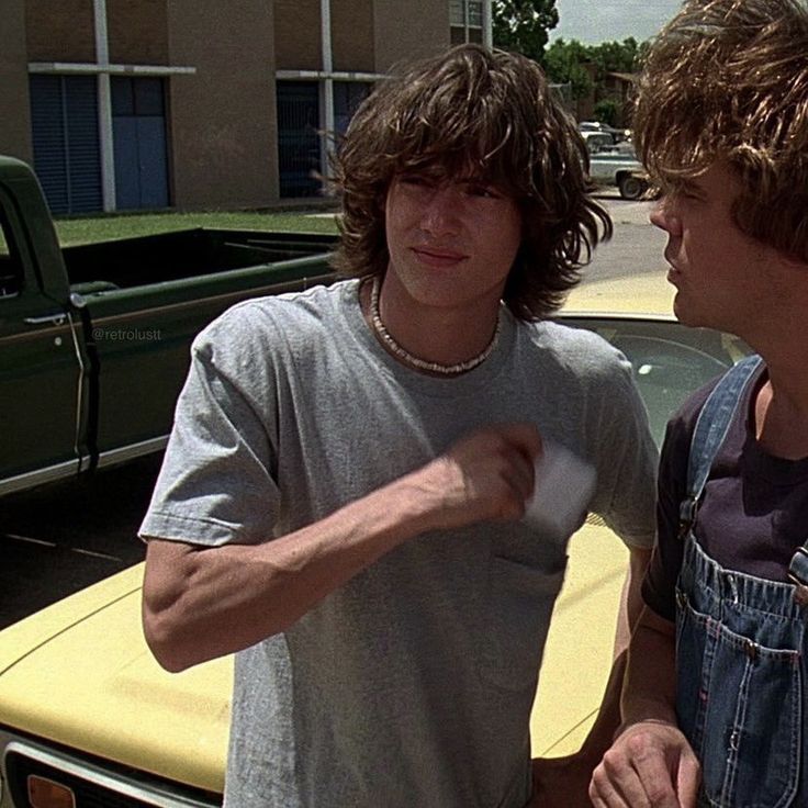 two men standing next to each other near a car