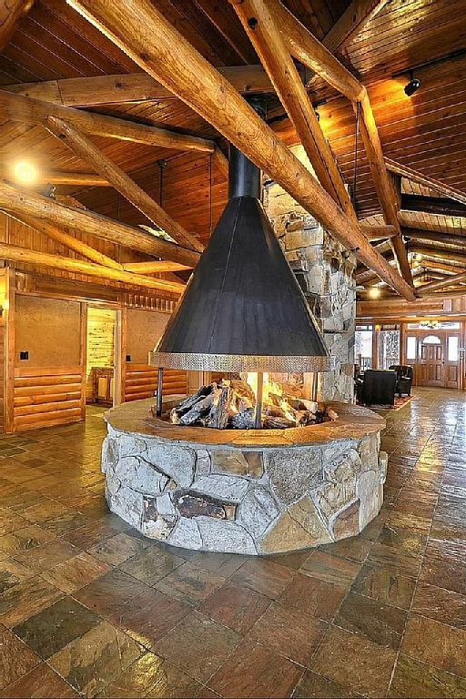 a large stone fireplace in the middle of a room with wood beams on the ceiling