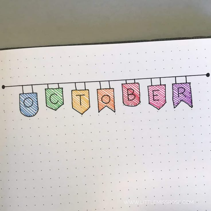 an open notebook with the word october written in colored pencils on top of it