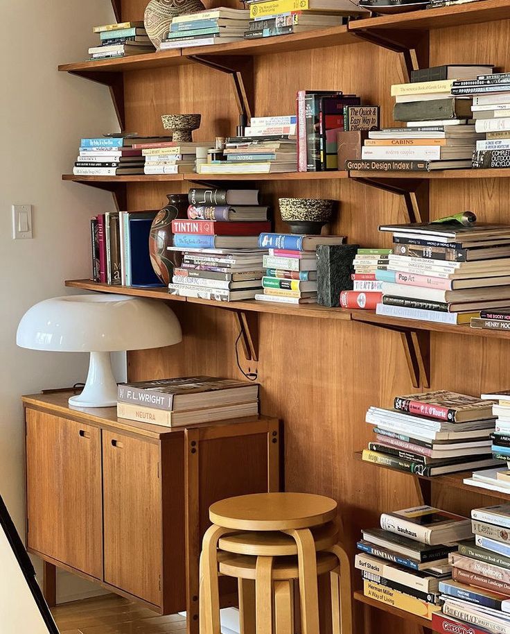 a bookshelf filled with lots of books next to a lamp and table top