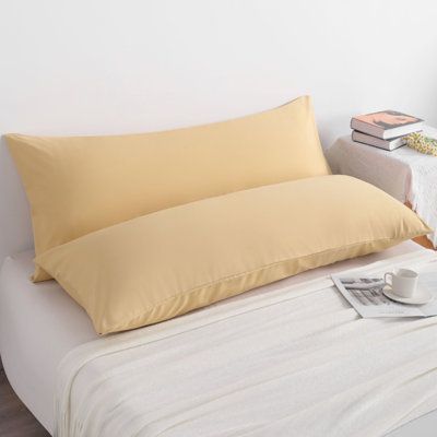 a bed with two pillows and a cup on it