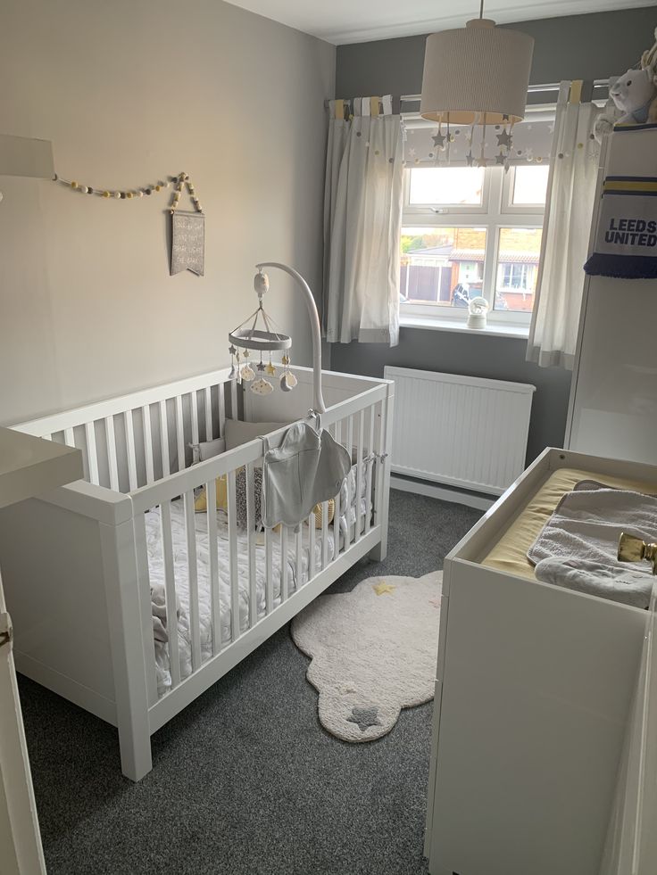 a baby's room with a white crib and grey carpeted flooring