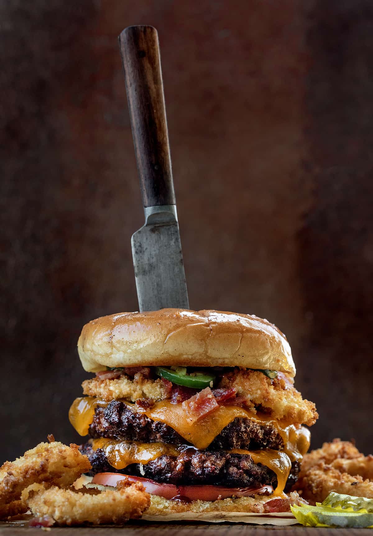 Rodeo Burger on a Cutting Board with a Serving Knife in It.