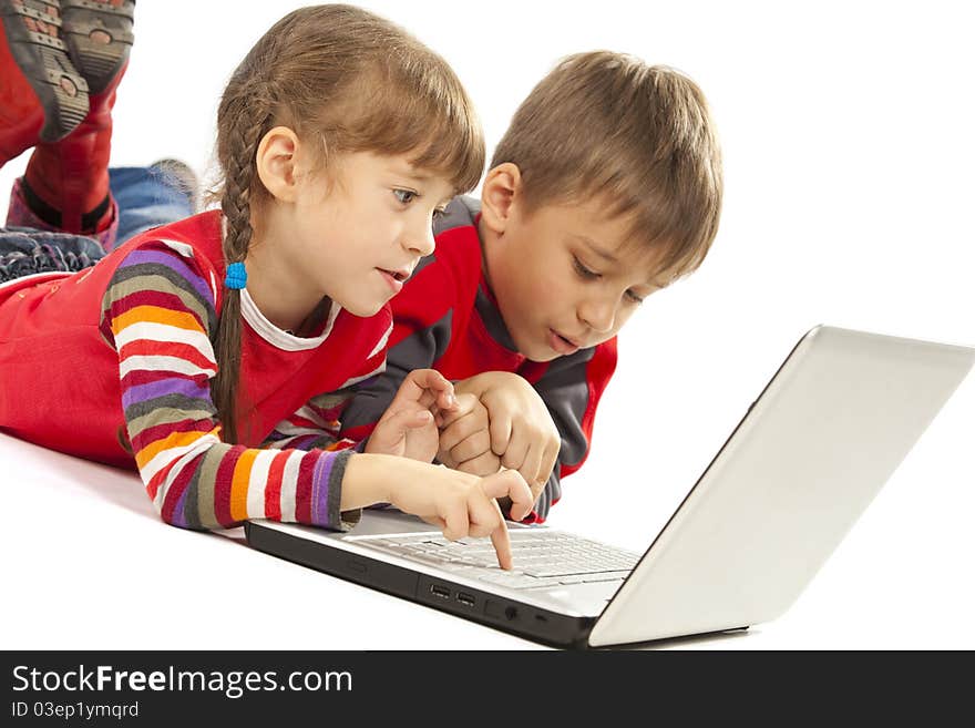 Two kids looking at notebook - laying flat on the floor. Two kids looking at notebook - laying flat on the floor