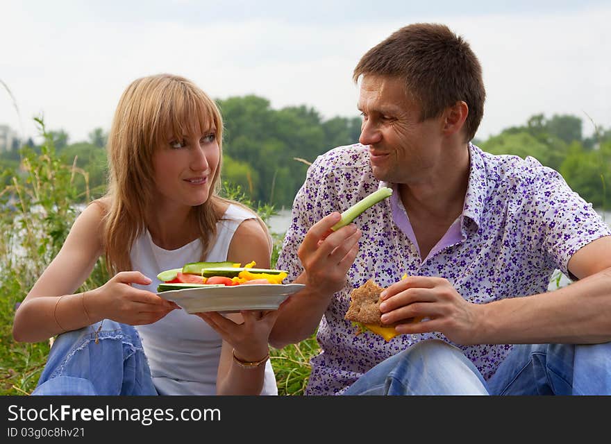 Young happy couple eating together outdoors