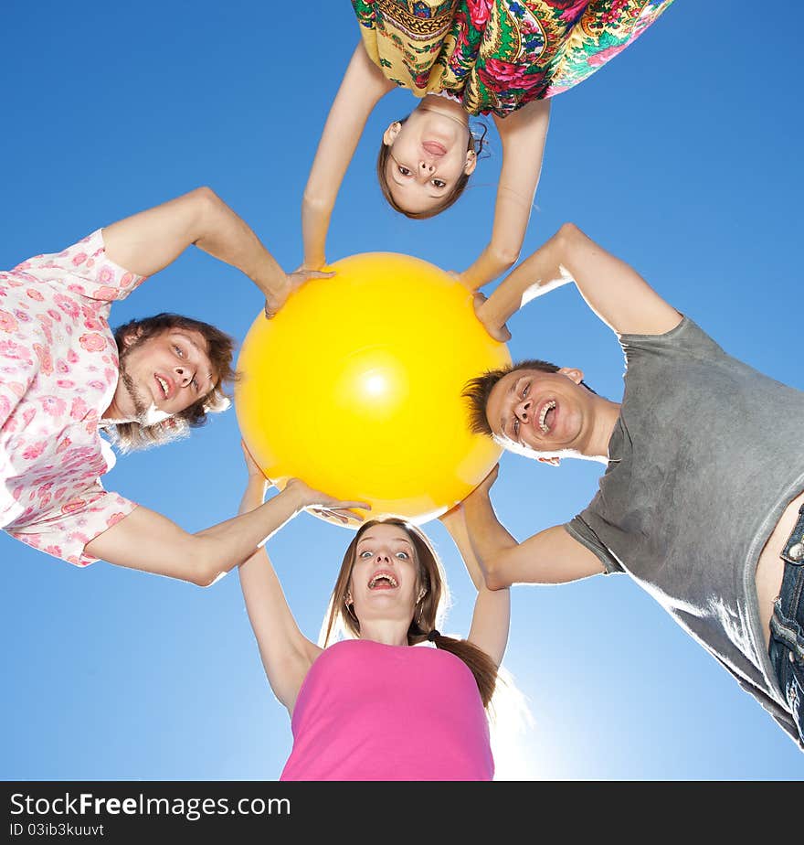 People hold yellow ball across sky