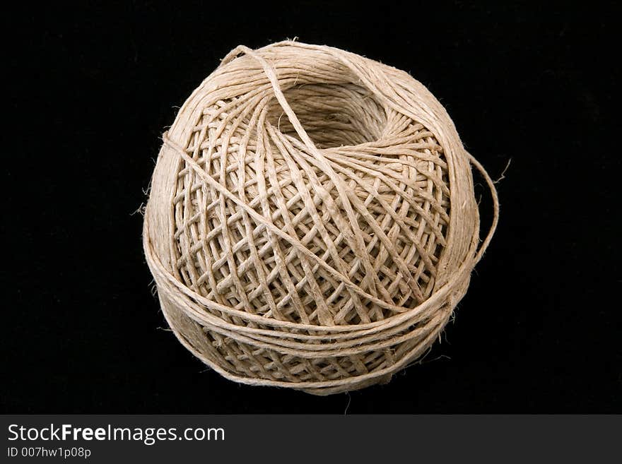 A large ball of neatly wound string on a black background.