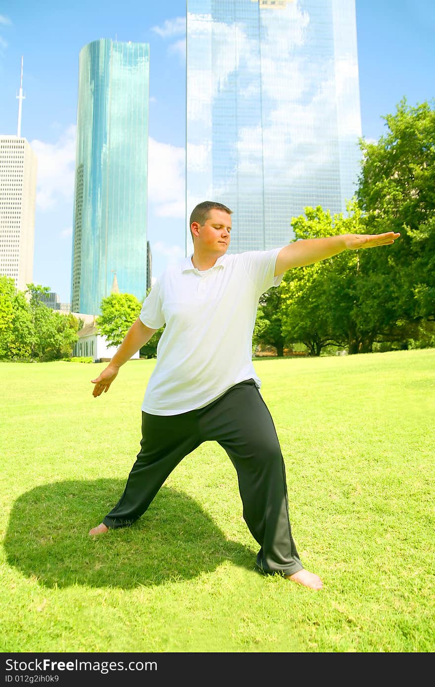 Handsome caucasian man meditate outdoor in a park with downtown building in the background. concept for yoga or wellbeing. Handsome caucasian man meditate outdoor in a park with downtown building in the background. concept for yoga or wellbeing