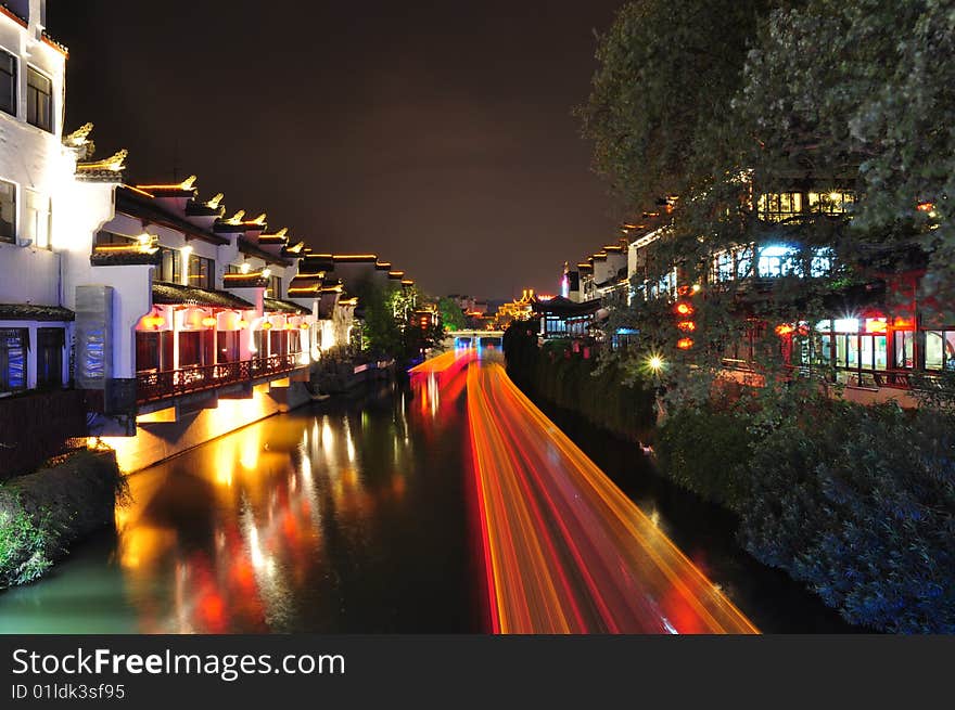 Night scene of Qinhuai river and the boats lights in long exposure. The Qinhuai River is the cradle of the culture of Nanjing. The Qinhuai River View Area has been the most flourishing place of Nanjing for more than 1,000 years, which is called “ten-kilometer-pearl-decorated curtains”. The most charming view on Qinhuai River is the boat whose name is “gaily-painted pleasure-boats”. They imitate the architectural of Ming Dynasty. The owners like to hang some colorful balls and lanterns on the boats. At night, the light is reflected into the water and adds much vitality to Qinhuai River.