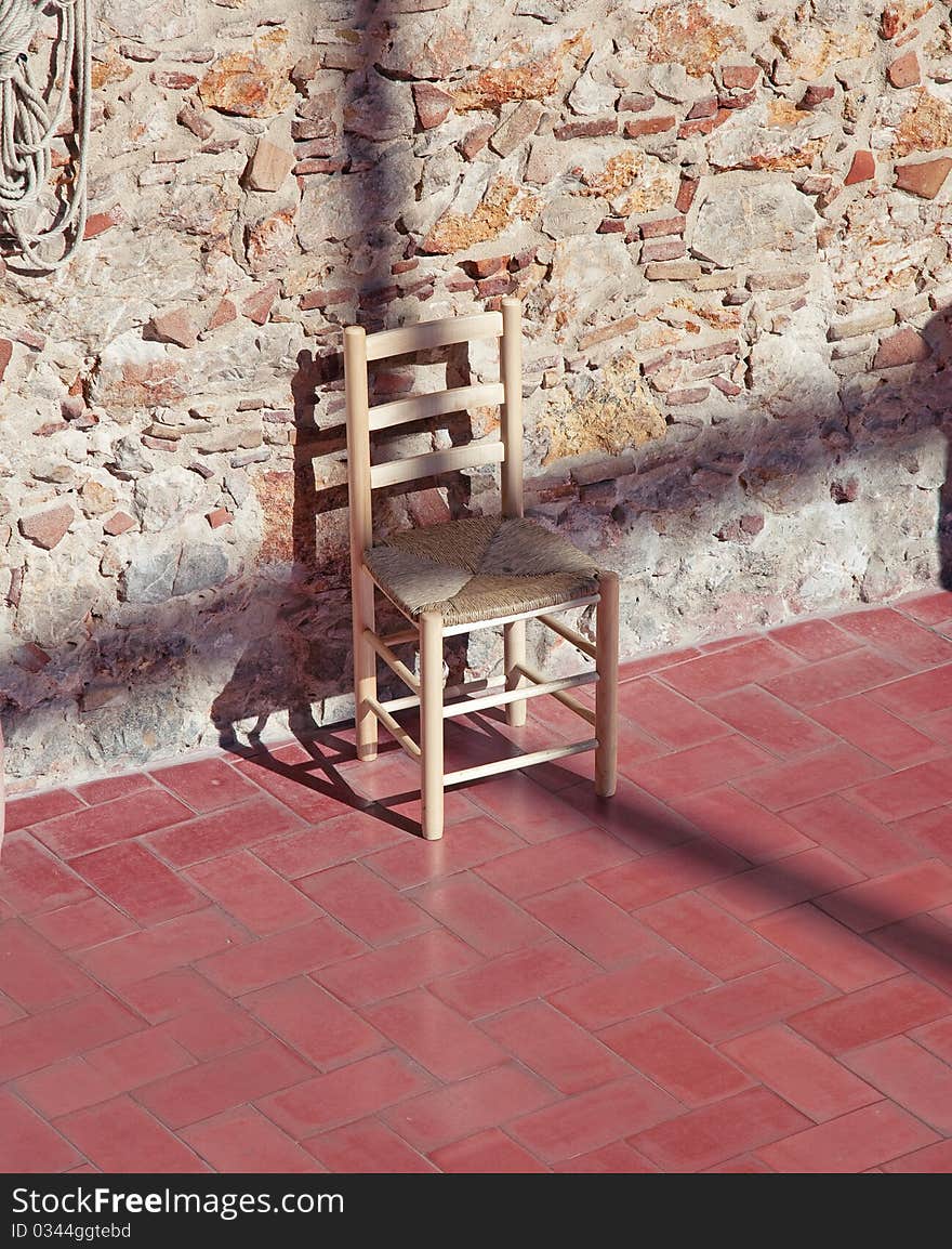 Cross - shaped shadow on the chair over stone wall photo