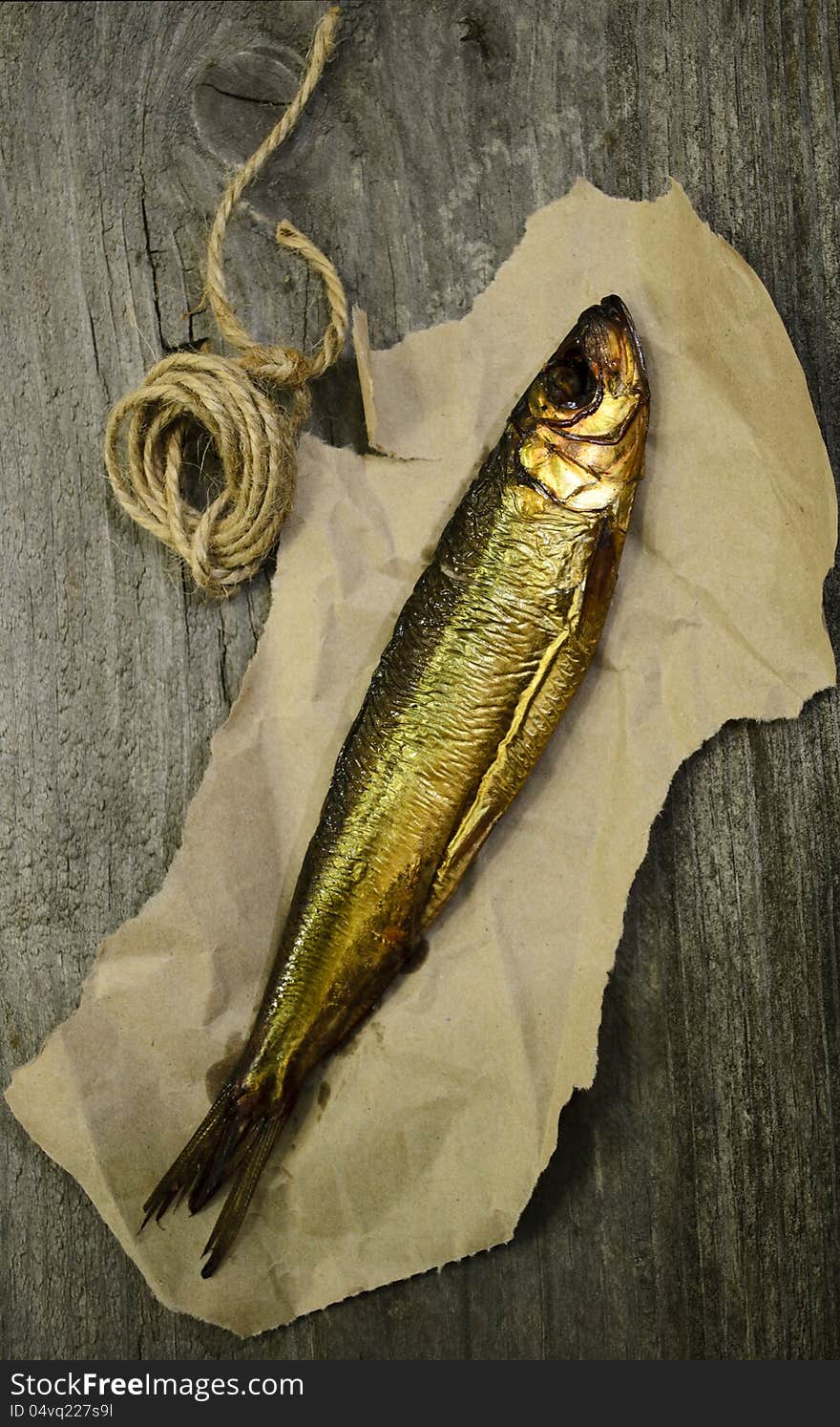 Fresh smoked baltic herring for the dinner on the paper with wooden background. Fresh smoked baltic herring for the dinner on the paper with wooden background