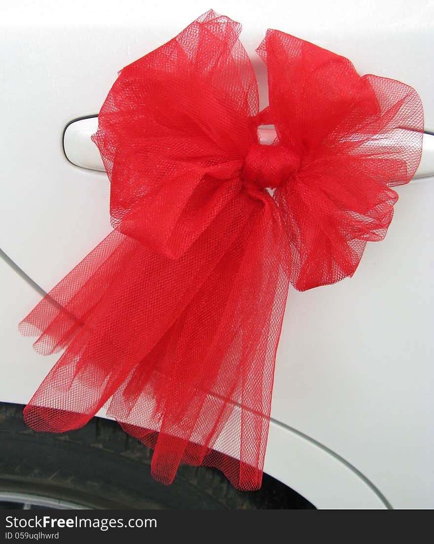 A red bow of lace ribbon for a wedding on a car. A red bow of lace ribbon for a wedding on a car