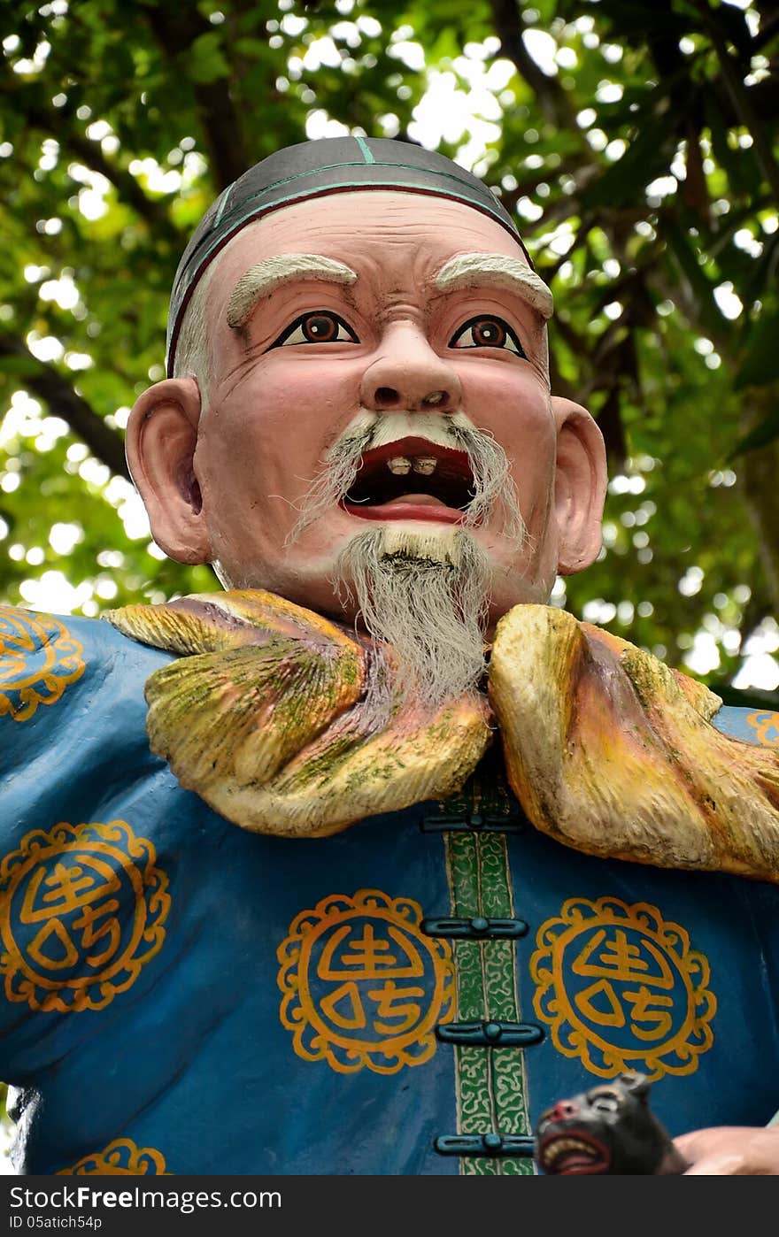 A statue of a Chinese man wearing a blue traditional Chinese buttoned robe and black cap. A statue of a Chinese man wearing a blue traditional Chinese buttoned robe and black cap.