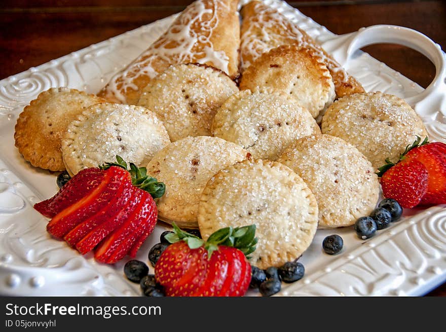 This is a platter of cookies sandwiches. one is the sugar cookie and glazed cookies with strawberry garnished