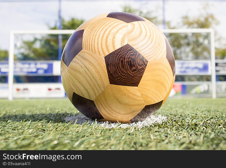 Wooden football lying on the penalty spot with the goal at the background. Wooden football lying on the penalty spot with the goal at the background