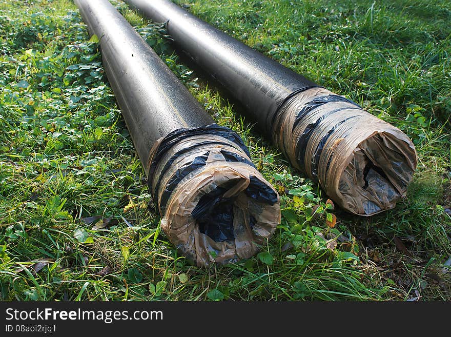 Two plastic pipes lying on the green grass on autumn day