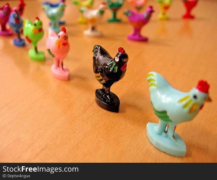 Colorful painted chicken or rooster figurines in line on wooden table. Colorful painted chicken or rooster figurines in line on wooden table.