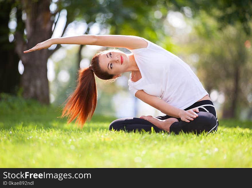 Yoga outdoor. Happy woman doing yoga exercises, meditate in the park. Yoga meditation in nature. Concept of healthy lifestyle and relaxation. Pretty woman practicing yoga on the grass