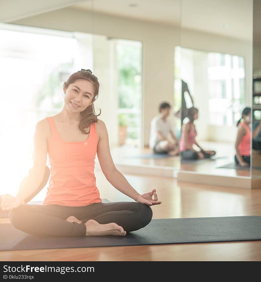 Attractive young Asian woman group exercising and sitting in yoga lotus position in yoga classes. asan. Attractive young Asian woman group exercising and sitting in yoga lotus position in yoga classes. asan