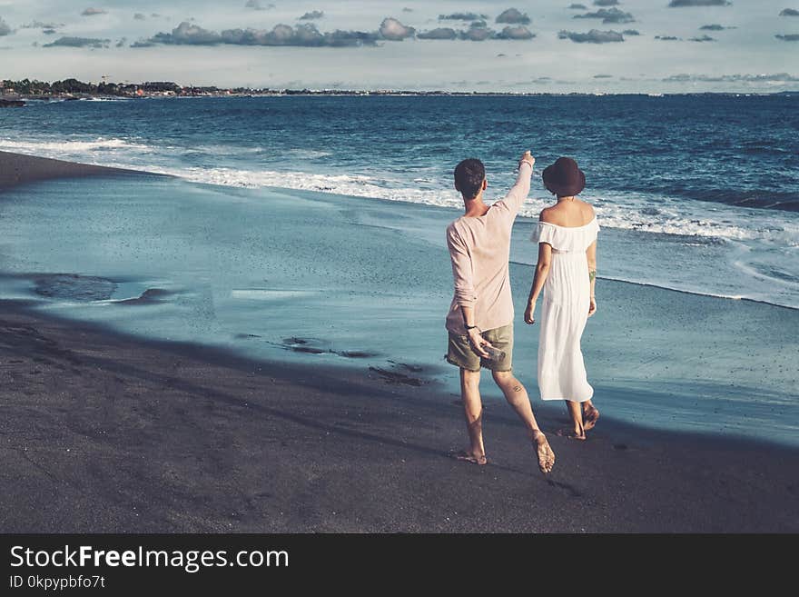 Couple walking on beach. Young happy couple walking on beach smiling holding around each other.