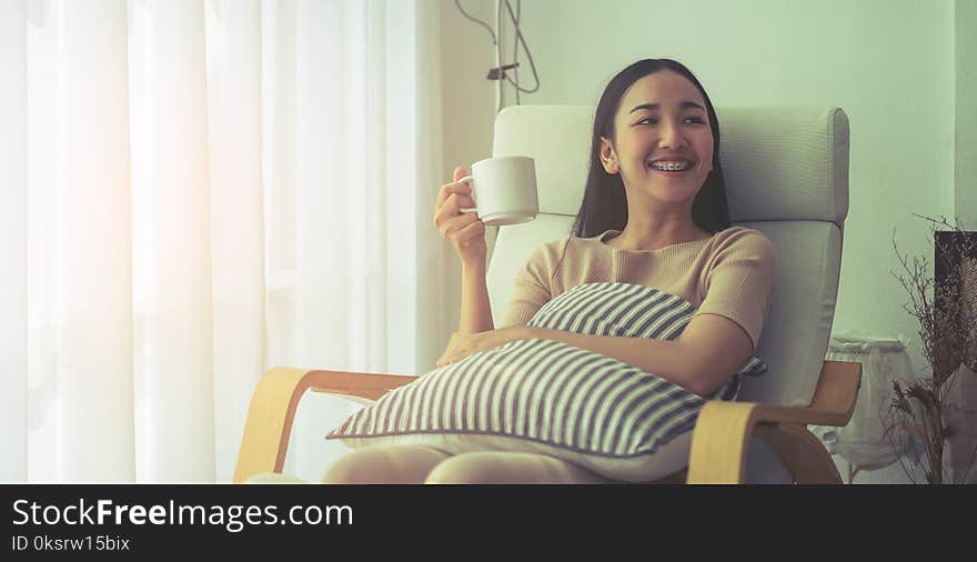 Smile girl on sofa sitting and drinking coffee by the wind