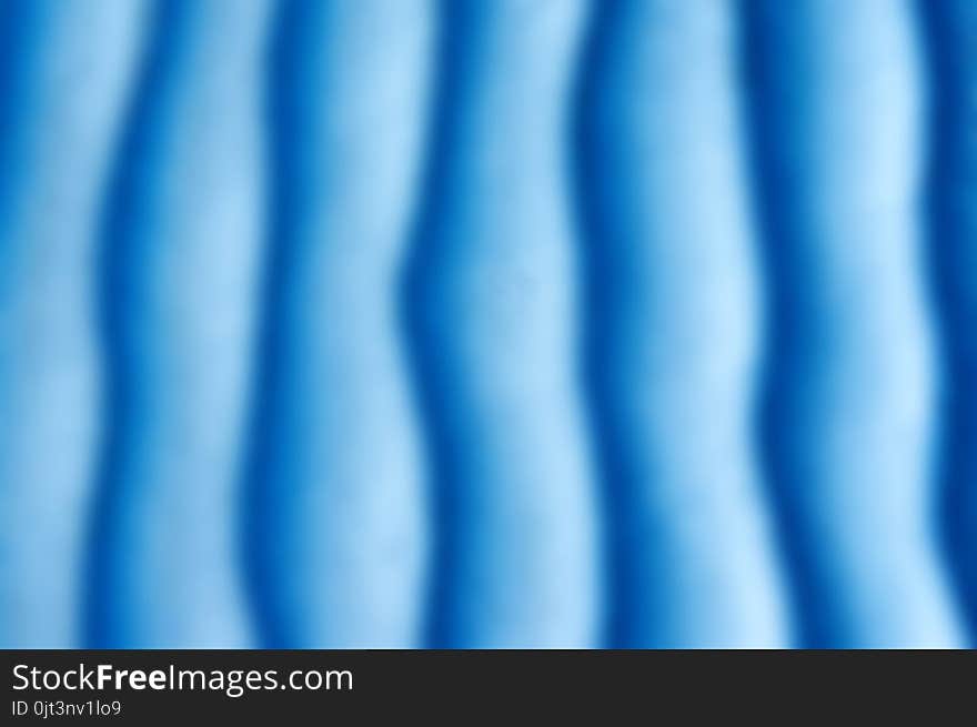 Blue sand texture. Background with Light blue fine sand. Sharp lines of waves on sand. Sand surface on the beach, view from above. Sandy structure outdoors on a sunrise time. Geometric pattern.