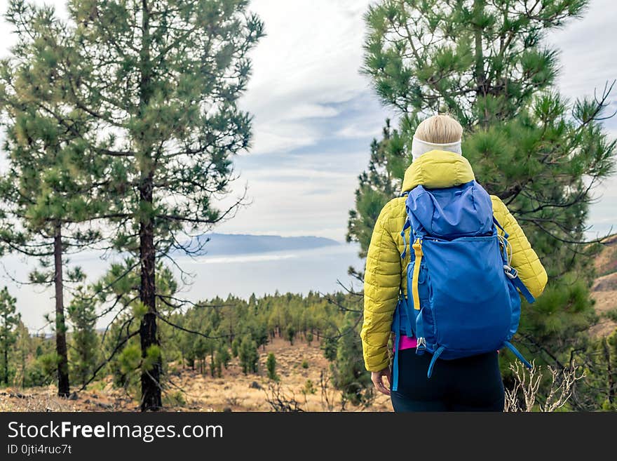 Hiking woman with backpack looking at inspirational mountains landscape and woods. Fitness travel and healthy lifestyle outdoors in fall nature. Female backpacker tourist walking in forest.