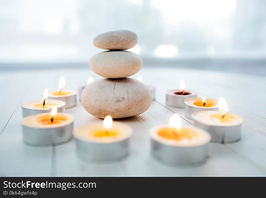 Zen Meditation Harmony, Spa Lifestyle, balanced stack of stones with aromatic candles on wooden white background. Zen Meditation Harmony, Spa Lifestyle, balanced stack of stones with aromatic candles on wooden white background