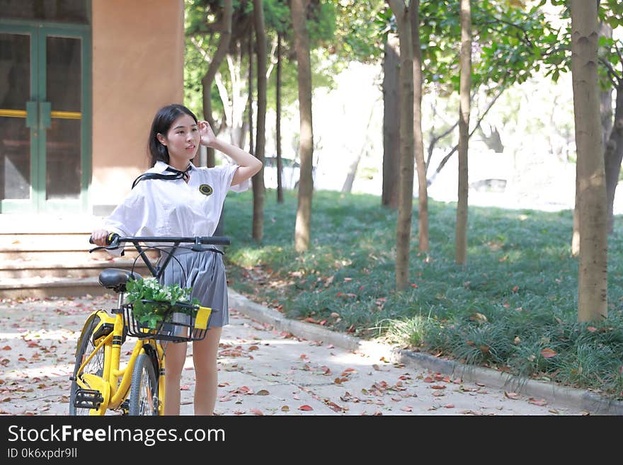 Relax Asian Chinese pretty girls wear student suit in school enjoy free time ride bike in nature spring garden