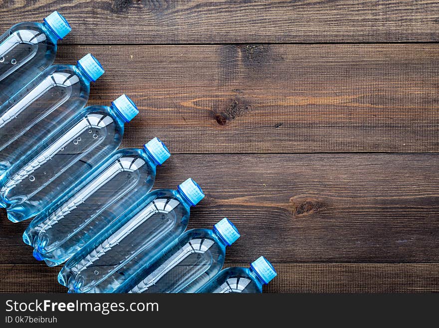 Drinking water in bottles on dark wooden background top view. Drinking water in bottles on dark wooden background top view.