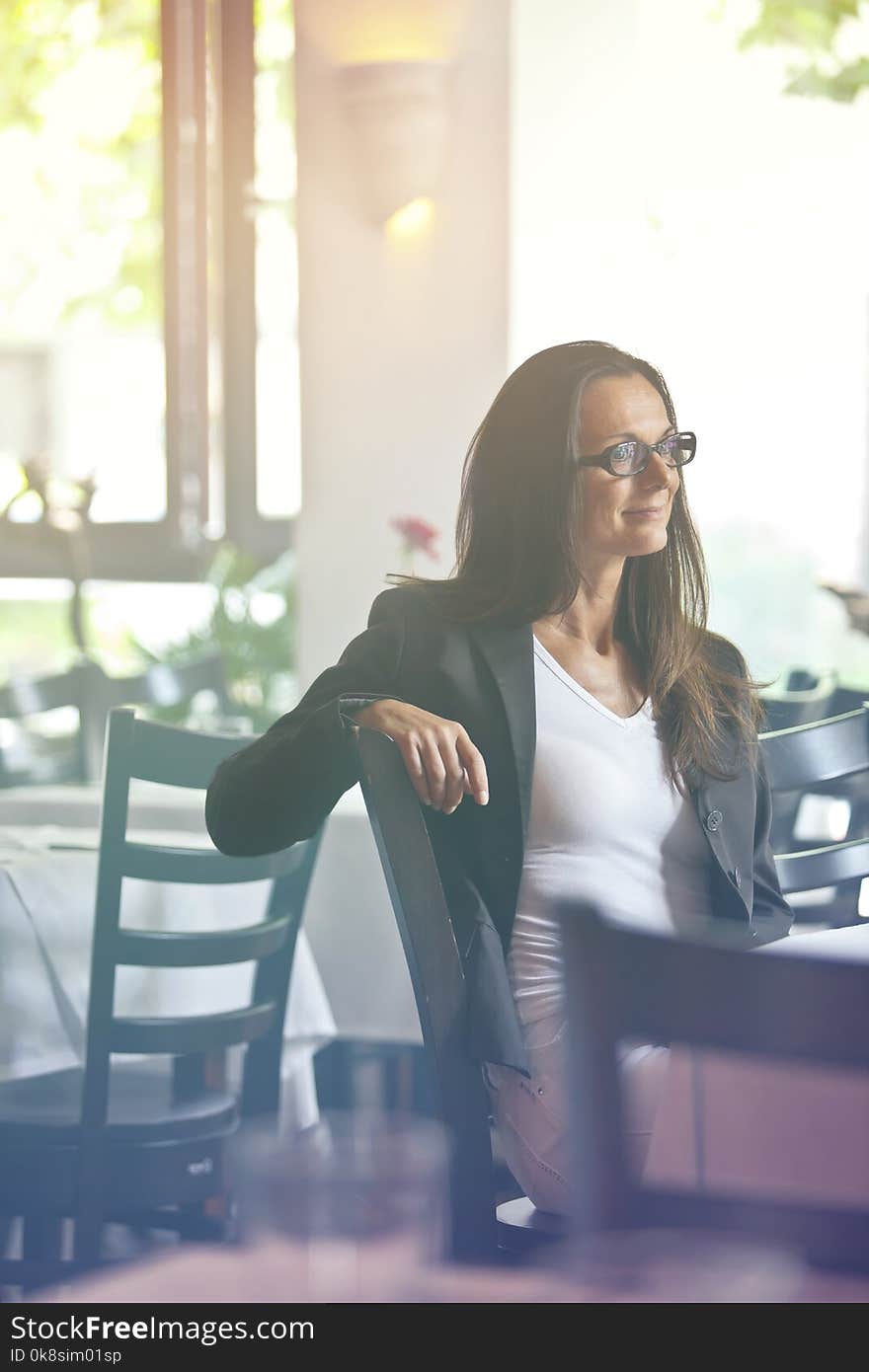 Portrait of a happy and pretty young woman sitting in a restaurant - perhaps she is the owner and just enjoys her break from work. Portrait of a happy and pretty young woman sitting in a restaurant - perhaps she is the owner and just enjoys her break from work.