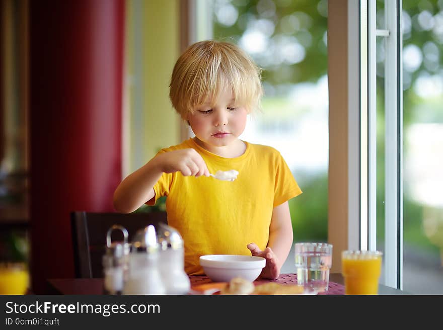 Little boy eating healthy breakfast in hotel restaurant. Tasty meal in home. Healthy food for kids